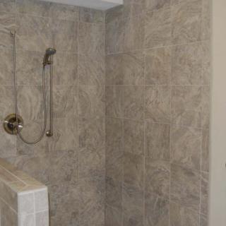 A tiled shower area with a handheld showerhead in a bathroom.