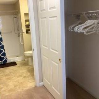 View of a closet with hangers near a bathroom.