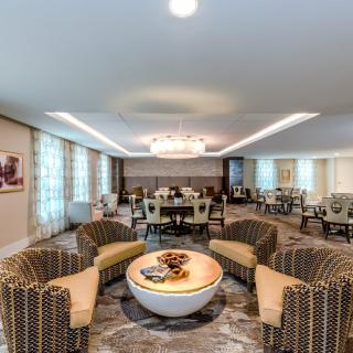 A modern living room with a central seating area, featuring a chandelier and stylish furniture.