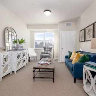 A stylish and inviting living room featuring a blue sofa, decorative accents, and ample natural light.