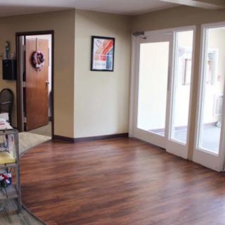 A well-lit office hallway with wooden flooring and large glass doors.