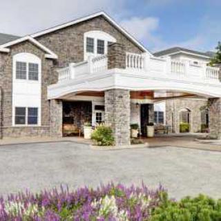 A modern residential building with stone facade and landscaped surroundings.
