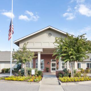 Front view of a building with an American flag and landscaped entrance.