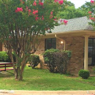 A brick house surrounded by a well-maintained yard with trees and flowers in bloom.