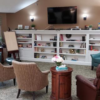 A cozy living room setup featuring comfortable seating, a wall-mounted television, and neatly organized shelves.