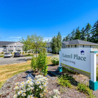 A view of a residential complex sign amidst landscaped greenery under a clear blue sky.