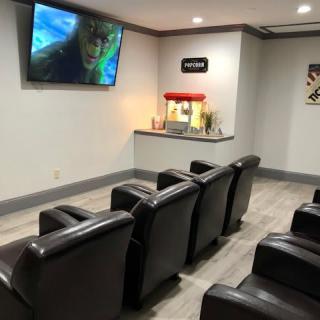 A cozy home theater setup with reclining chairs, a large TV screen, and a popcorn machine.