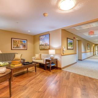 A well-lit hallway with a cozy seating area and artwork on the walls.