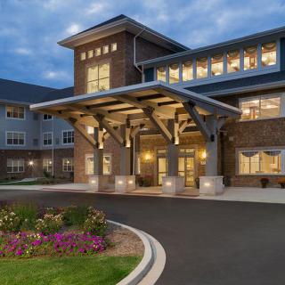 A well-lit residential building entrance with landscaped surroundings during the evening.