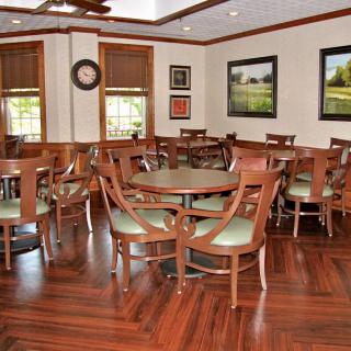 A cozy dining area with wooden flooring, surrounded by tables and chairs, adorned with wall art.