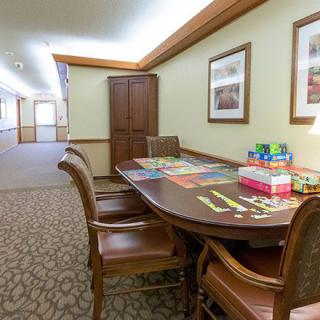 A conference room with a table, chairs, and board games set up, adjacent to a hallway.