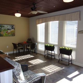 A bright sunroom with wicker furniture and large windows allowing abundant natural light.
