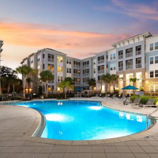 A modern apartment complex with a swimming pool at sunset.