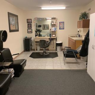 A cozy salon space featuring styling chairs, a large mirror, and a welcoming atmosphere.