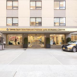 Entrance of a hotel with signage and a car parked outside.