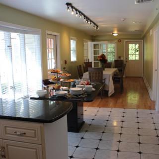 A spacious kitchen and dining area with ample natural light, featuring a black countertop, tiled and hardwood flooring, and a large dining table.