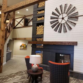 A cozy rustic living room featuring a fireplace, wooden beams, and windmill wall decor.