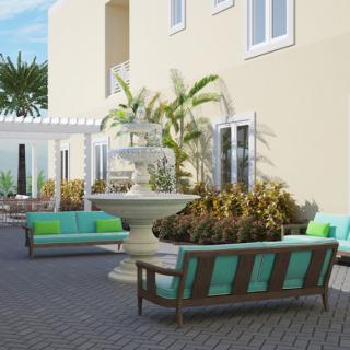 A serene outdoor patio with comfortable seating and a central fountain surrounded by lush greenery.