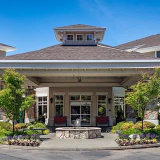 A well-landscaped entrance to a residential building under a clear blue sky.