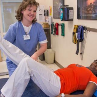 A healthcare professional assists a patient with physical therapy exercises.