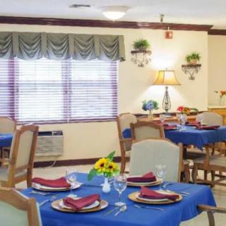 A neatly arranged dining room with blue tablecloths and elegant table settings.