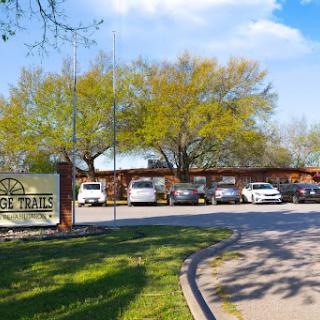 A scenic view of a building surrounded by trees and parked cars.