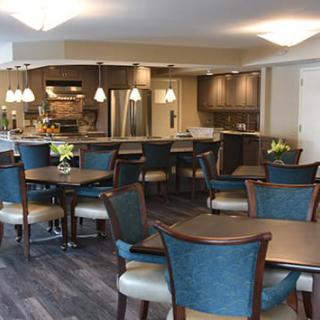A modern dining area with tables and chairs, adjacent to a kitchen.