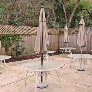An outdoor patio area with several tables and umbrellas surrounded by a wooden fence.