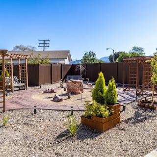 A well-designed outdoor garden space featuring a mix of plants, rocks, and wooden structures.