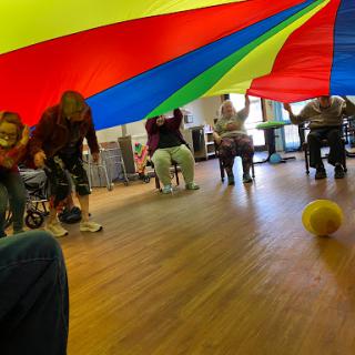 Participants engage in a fun and interactive game under a colorful parachute.