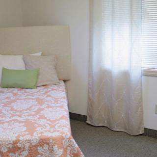 A cozy bedroom featuring a neatly made bed with pillows next to a window with curtains.