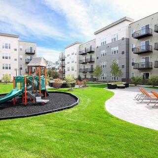 Modern apartment complex with a playground and green landscaped area.