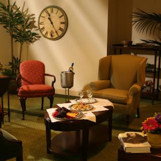 A cozy living room setup featuring a clock, comfortable chairs, and a decorative table with snacks.