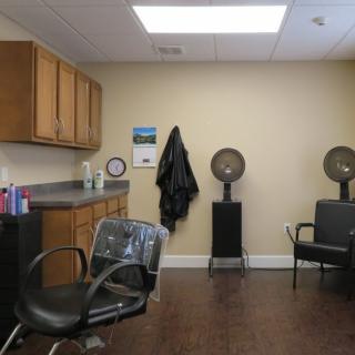 A cozy salon interior with chairs, hair dryers, and a counter with hair products.