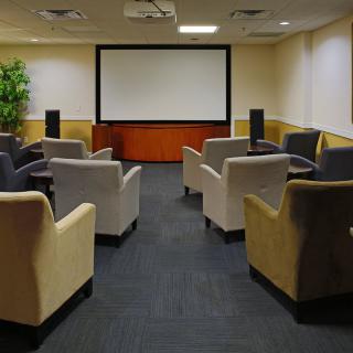 A cozy home theater setup with comfortable armchairs facing a large projector screen.