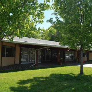 A sunny day view of a building surrounded by trees and a well-maintained lawn.