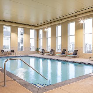 A serene indoor swimming pool, complete with lounge chairs and large windows allowing natural light to fill the space.