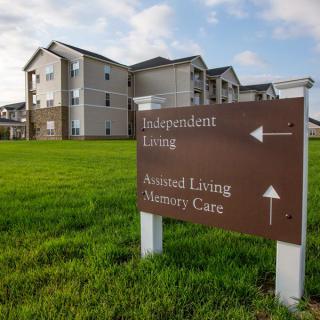 A directional sign in front of a retirement community complex indicating directions to independent living, assisted living, and mature care facilities.