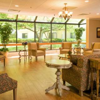 A spacious and well-lit lobby with comfortable seating and large windows overlooking a garden.