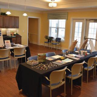 A room set up for a small event with tables, chairs, and exhibits on display.