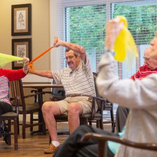 A group of seniors engaging in a fitness exercise using resistance bands indoors.