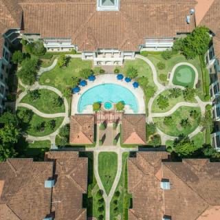 Aerial view of a landscaped courtyard with a swimming pool surrounded by greenery and architectural structures.