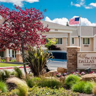 Entrance of a residential or community building with landscaped surroundings and an American flag.