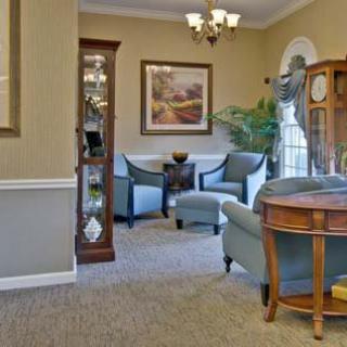 A cozy living room with traditional furniture and decor, featuring a seating area and greenery.