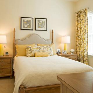 A cozy bedroom with a neatly made bed, warm lighting, and decorative accents.