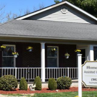 A small house with a porch and well-maintained lawn on a sunny day.