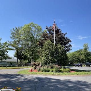 A serene view of a landscaped roundabout surrounded by lush greenery under a clear blue sky.