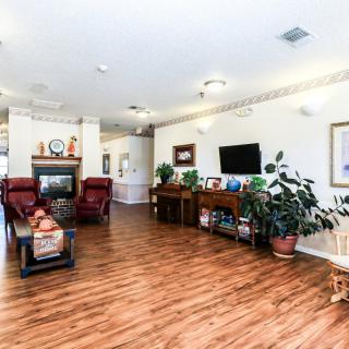 A spacious living room with hardwood flooring, featuring comfortable seating, a TV, and decorative elements.