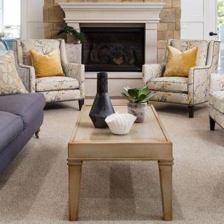 A cozy living room with a stylish arrangement of furniture, featuring a fireplace, armchairs with yellow pillows, and a wooden coffee table.
