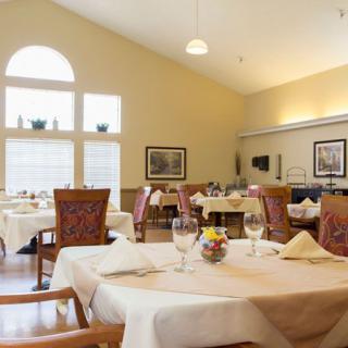 A spacious dining room with elegantly set tables and large windows letting in natural light.